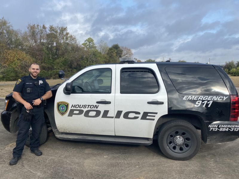 Parker standing by his police car in uniform