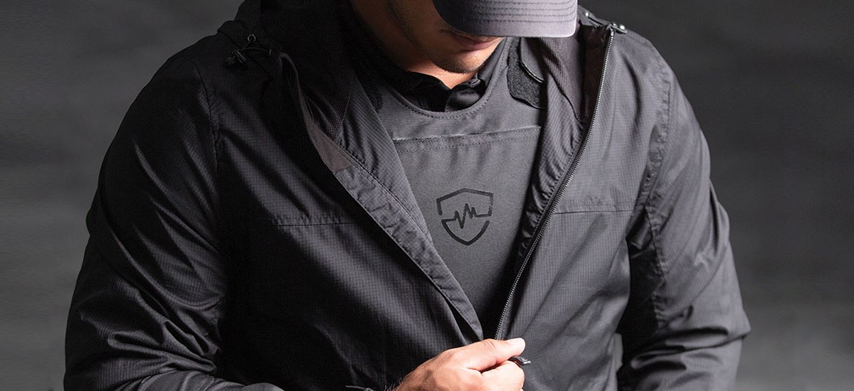 Man zipping up jacket over body armor